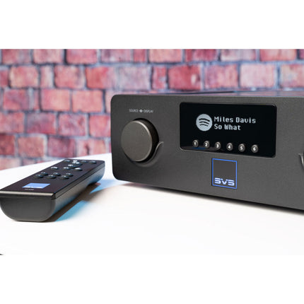 SVS Prime Wireless Pro Soundbase, aparatul pe un blat, cu display-ul afișând o piesă redată prin Spotify