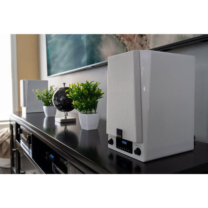 SVS Prime Wireless Pro, finisaj Piano Gloss White, boxa în prim-plan pe o comodă, cu televizorul în fundal