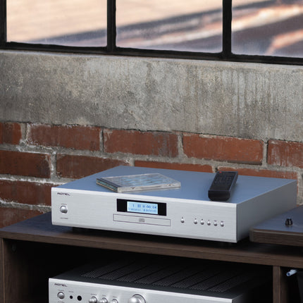 Rotel CD11MKII argintiu, cu o carcasă de CD și telecomanda deasupra, pe un amplificator Rotel A11MKII