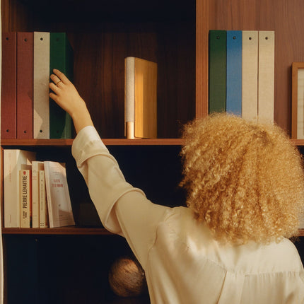 Beosound Emerge în finisaj Gold Tone, pe un raft de bibliotecă
