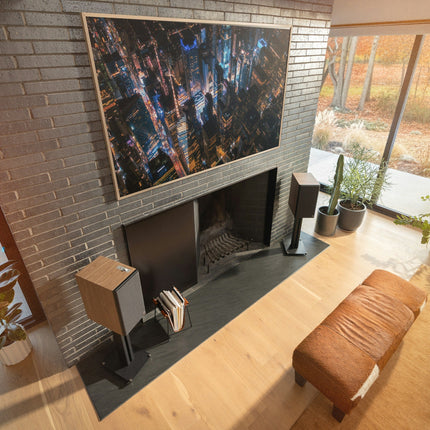 Pereche Klipsch The Nines II pe stative, sub un televizor mare intr-un living cu semineu