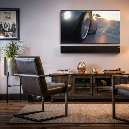 Klipsch Heritage Theater Bar montat pe perete sub un televizor, cu un receiver AV si un subwoofer in aceeasi incapere
