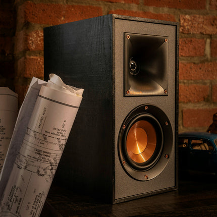 Prim-plan cu o incinta Klipsch R-51PM, cu pavilionul Tractrix si woofer-ul de cupru in lumina calda