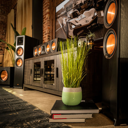 Canal central Klipsch Reference Premiere pe o comoda sub televizor, alaturi de boxele de podea din aceeasi gama