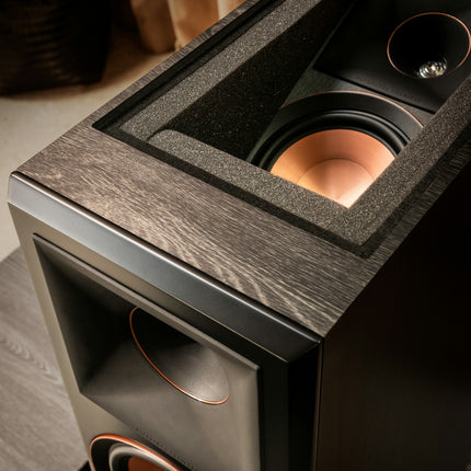 Prim-plan pe modulul Dolby Atmos orientat in sus, cu wooferul si hornul cu tweeter vizibile