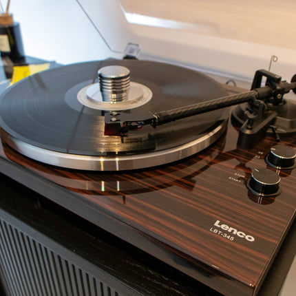Lenco LBT-345 în finisaj nuc, cu stabilizatorul cromat pe un disc de vinil și brațul din fibră de carbon