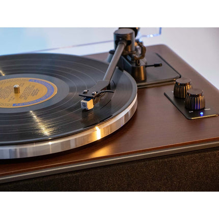 Doza Lenco LS-470 pe un disc de vinil, lângă marginea platanului din aluminiu și butoanele de pe partea de sus