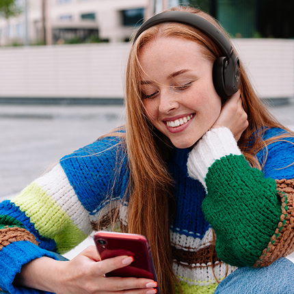 Căști JBL Tune 680NC negre, purtate pe stradă, cu telefonul în mână