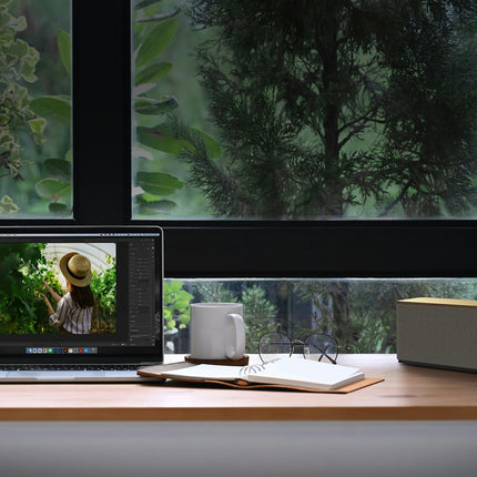 Boxa Klipsch The One Plus in finisaj Walnut, pe un birou de lemn langa un laptop