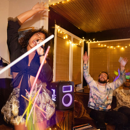 Boxa Klipsch Vegas pe stativ, la o seară de karaoke, cu iluminarea violet aprinsă