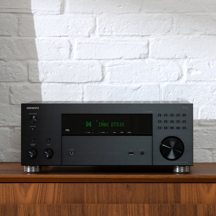 Receiverul Onkyo TX-RZ30 pe o comoda de lemn, langa un perete de caramida alba