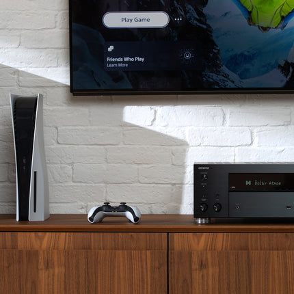 Receiverul Onkyo TX-RZ30 alaturi de o consola de jocuri, cu afisajul indicand Dolby Atmos