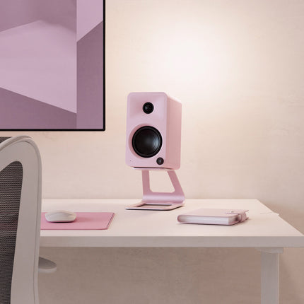 Boxă activă Kanto Audio ORA roz, pe un stand de birou, lângă un monitor