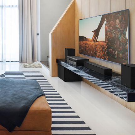 Boxa Klipsch R-50M cu grila montata pe o consola sub un televizor, intr-un sistem cu receiver AV