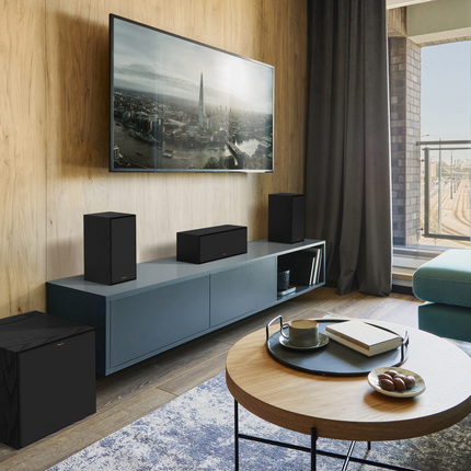 Perechea Klipsch R-50M cu grilele montate, la capetele unei comode sub televizor, intr-un sistem home cinema