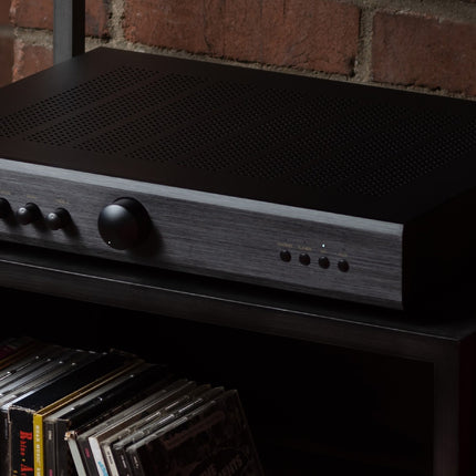 Rotel A10MKII negru pe un raft, deasupra unor CD-uri