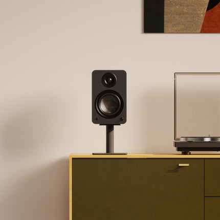 Boxă neagră pe un stativ Kanto Audio SP6HD negru, pe o comodă