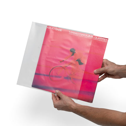 Folie translucidă Kanto Audio TT-CS20 trasă peste coperta unui vinil de 12 inch, ținută în mâini