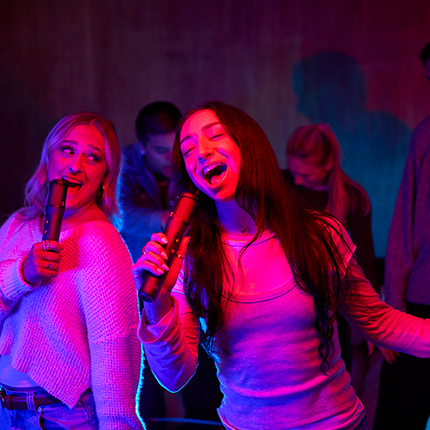 Prieteni care cântă karaoke cu microfoanele JBL EasySing Mics