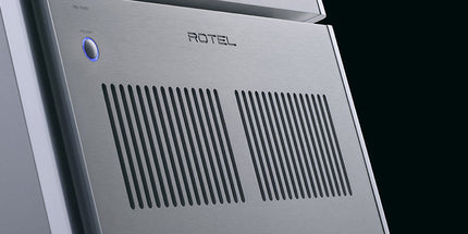 Rotel RB-1590 argintiu, detaliu din unghi al panoului frontal, cu butonul de pornire iluminat și grilele de ventilație