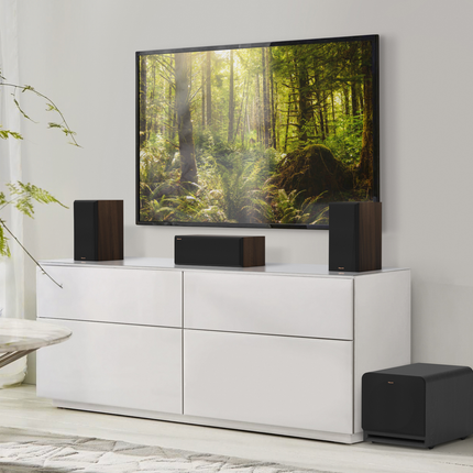 Cameră minimalistă cu televizor, boxe Klipsch pe comodă și un subwoofer pe pardoseală