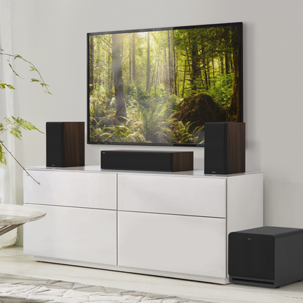 Klipsch RP-1200SW pe podea, lângă o comodă TV cu boxe Klipsch