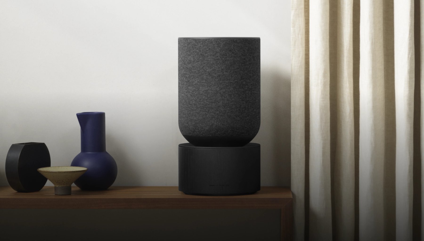 Beosound Balance din stejar negru și textil, pe o comodă de nuc, lângă ceramică daneză.